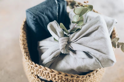 A photo of two presents wrapped in different coloured fabrics in a basket