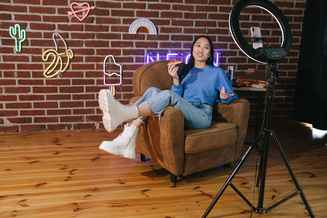 A photo of an influencer sitting in an armchair filming herself