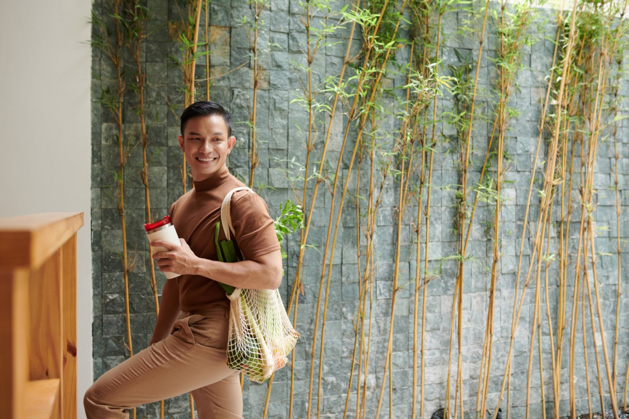 Person standing with a tote bag holding a coffee cup