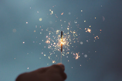 A hand holding a lit sparkler